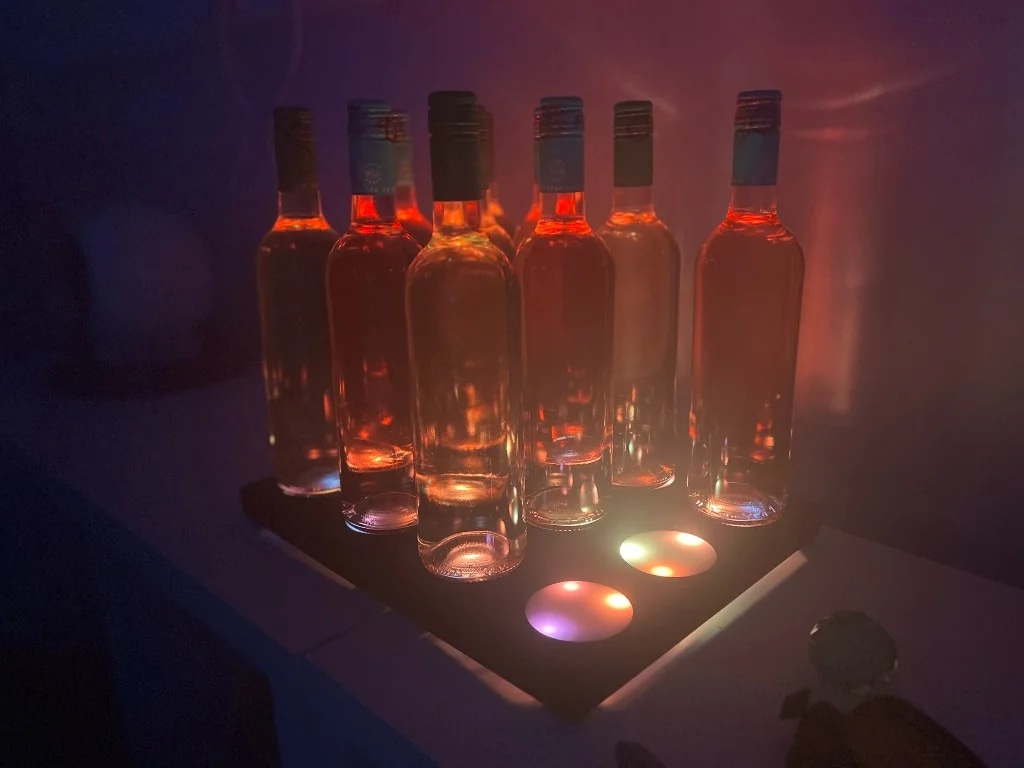 Sauternes Wall — bouteilles de rosé rétro-éclairées sur socle lumineux